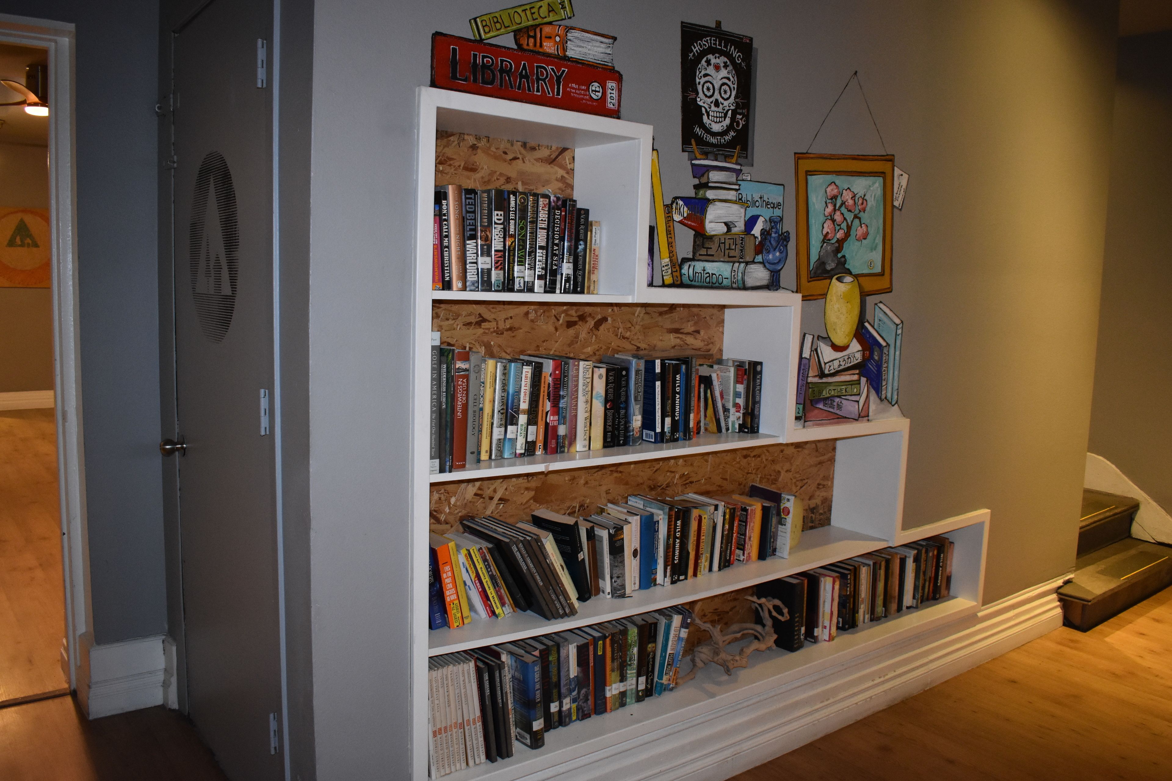 Une bibliothèque remplie de livres et d’objets décoratifs, notamment un crâne et un tableau encadré.