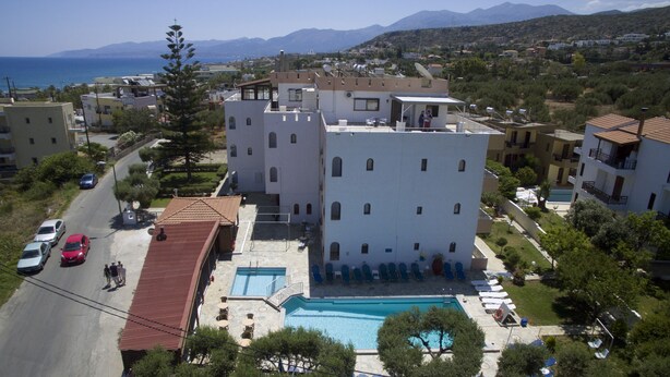 Un immeuble résidentiel doté d’une piscine, d’une toiture rouge et offrant une vue sur la mer.