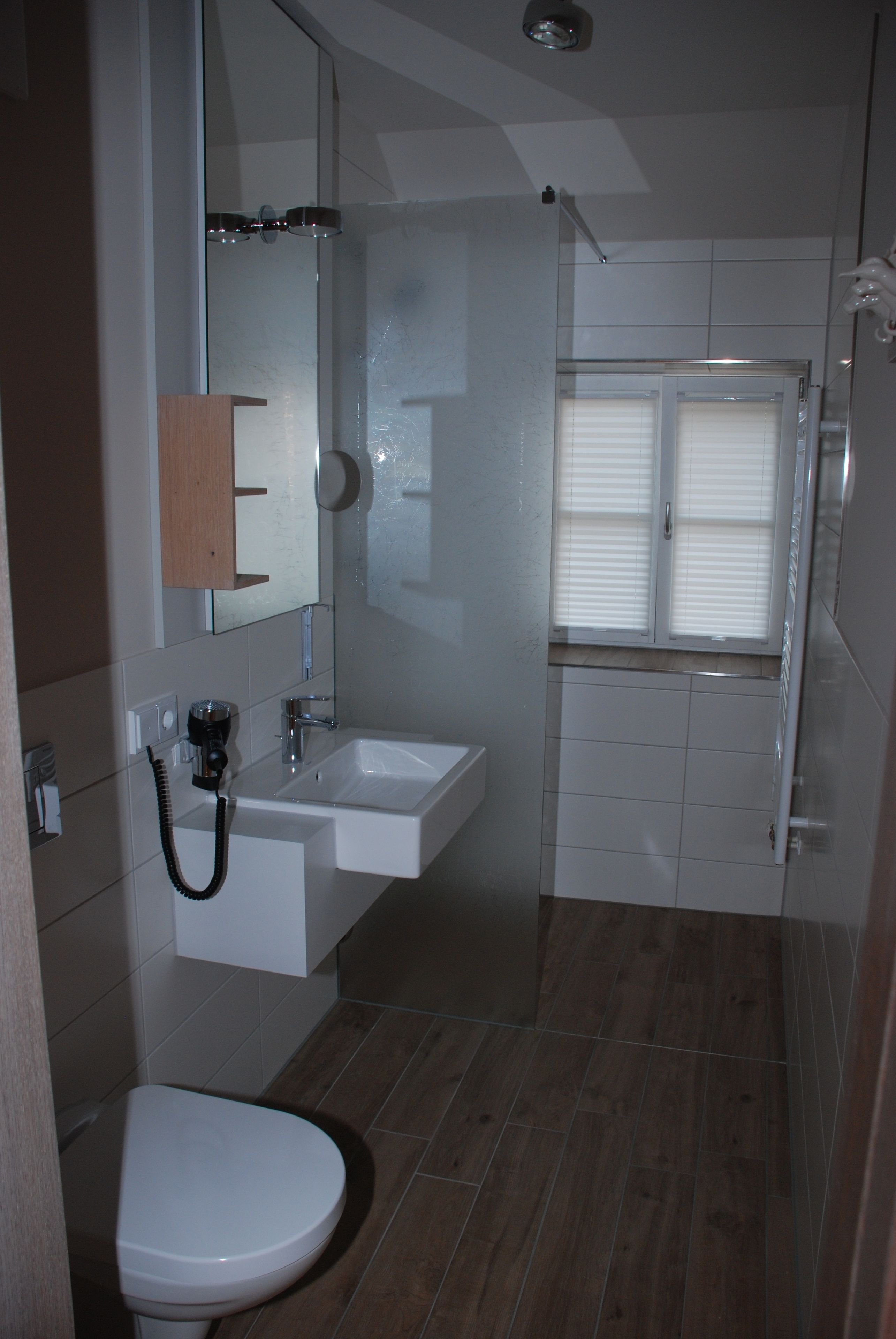 Baño con inodoro, lavabo, espejo y ducha.