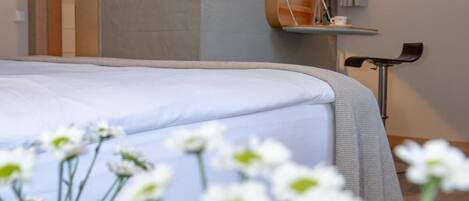 A hotel room with a bed, bedside table, and a window.