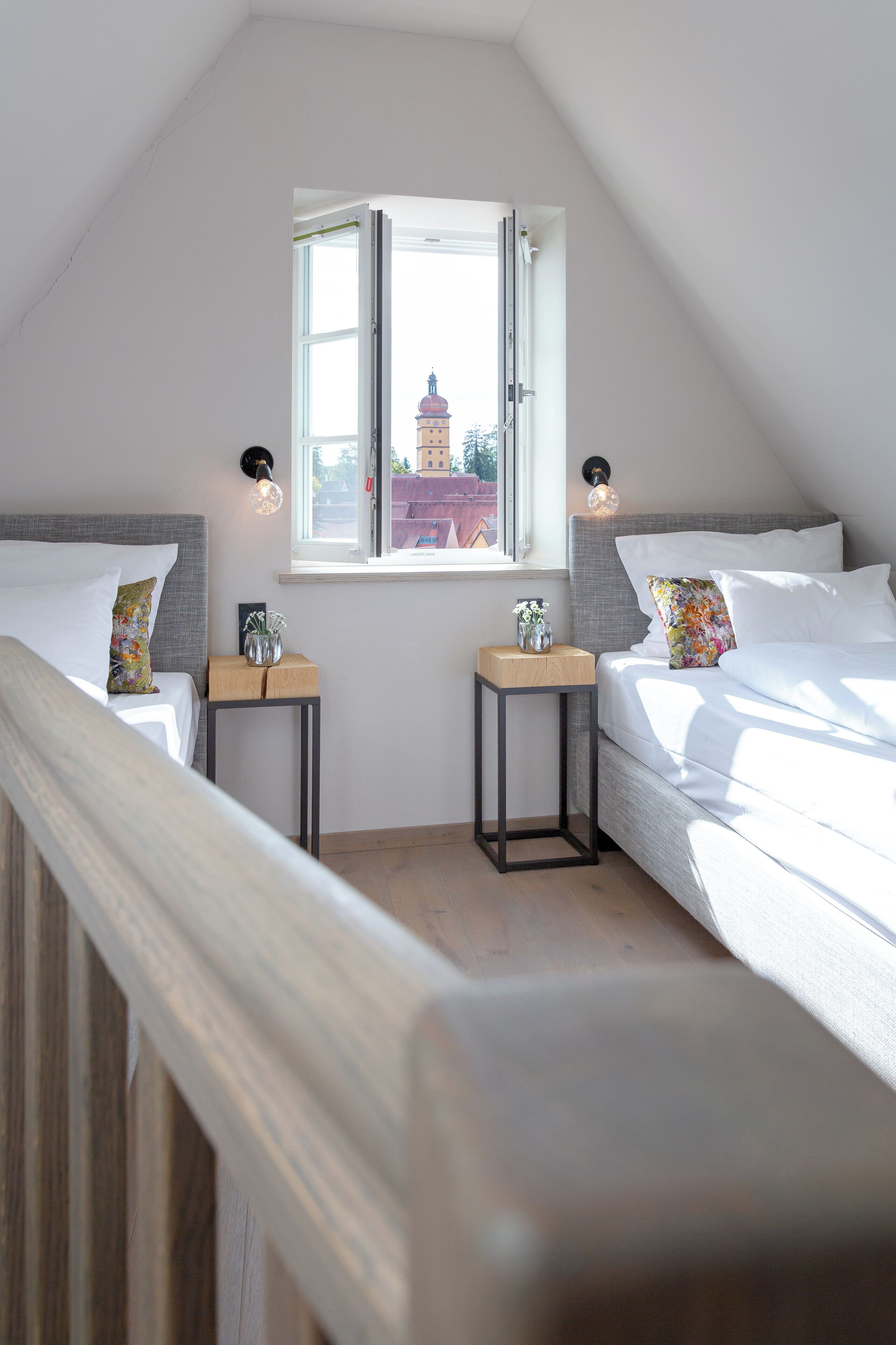 A bedroom with two beds, a window, and a view of a building outside.