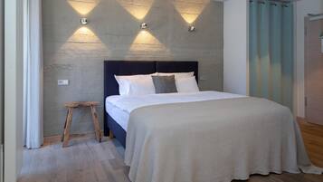 A bedroom with a bed, a nightstand, and a wall-mounted light fixture.