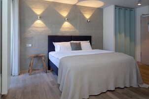 A bedroom with a bed, a nightstand, and a wall-mounted light fixture.