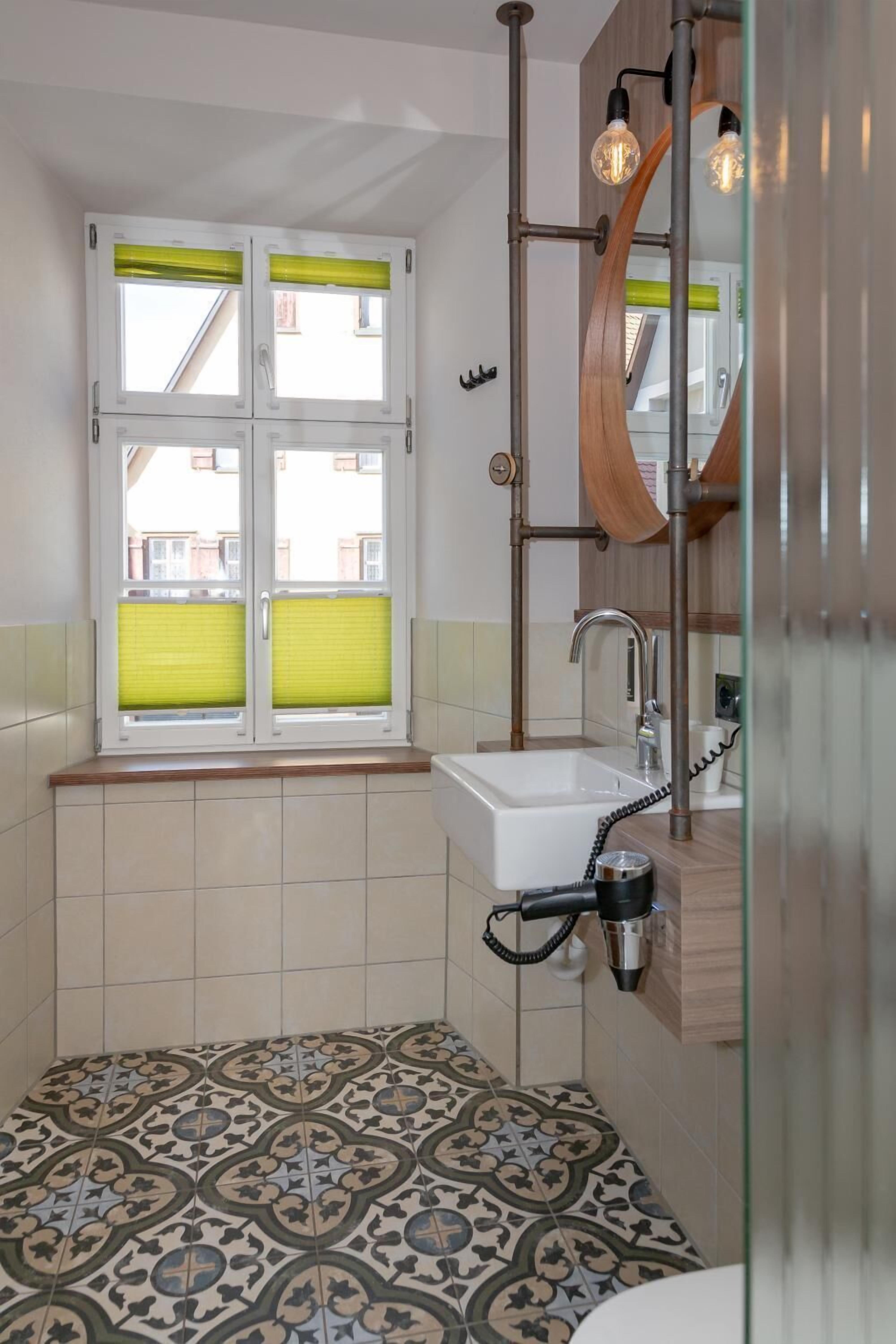 A bathroom with a window, a sink, and a hairdryer.