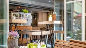A modern outdoor seating area with wooden tables and benches, a chalkboard sign, and a potted plant. - Hotel Luise & Luisenhof (Dinkelsbuehl)
