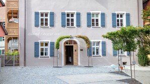 A hotel with a tiled roof, multiple windows with shutters, and a cobblestone courtyard. - Hotel Luise & Luisenhof (Dinkelsbuehl)