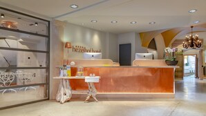 A hotel reception area with a modern design, featuring a wooden reception desk, a glass partition, and a chandelier. - Hotel Luise & Luisenhof (Dinkelsbuehl)