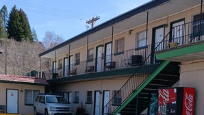Un motel con aparcamiento, una máquina expendedora de Coca-Cola y una escalera que lleva al piso superior.