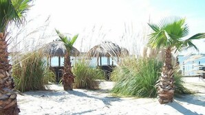 Een strand met rieten hutten en palmbomen.