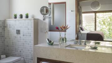 A modern bathroom with a white toilet, a sink with a mirror, and a window providing natural light.