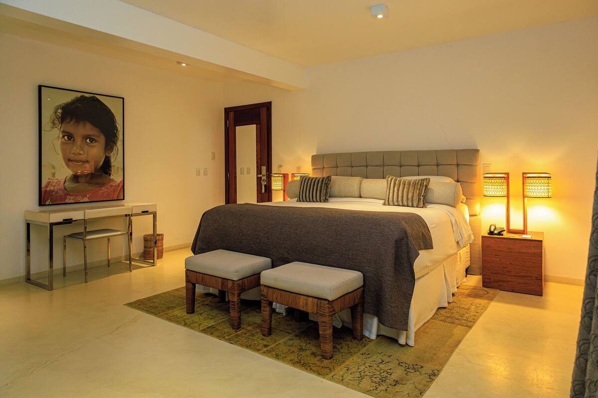 A bedroom with a bed, bedside tables, a desk, and a chair.