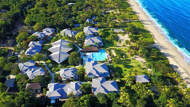 Une vue aérienne d’un complexe hôtelier comprenant plusieurs bâtiments, une piscine et une plage.
