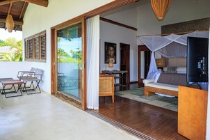 Una habitación con cama, televisor, mesa de comedor y vistas al exterior.