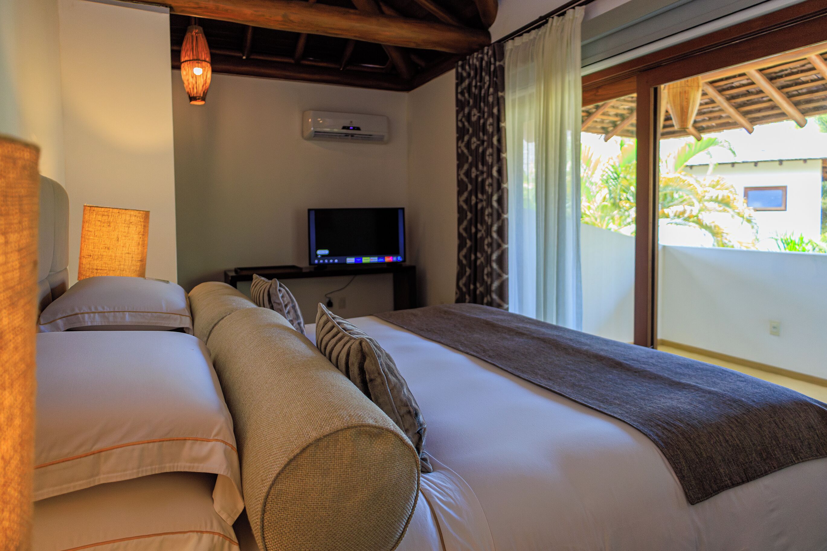 Una habitación de hotel con una cama, televisión y ventana con cortinas.