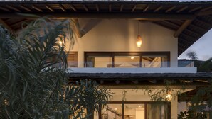 Une maison moderne dotée d’un vaste patio, d’un coin repas et d’une grande fenêtre donnant sur l’intérieur.