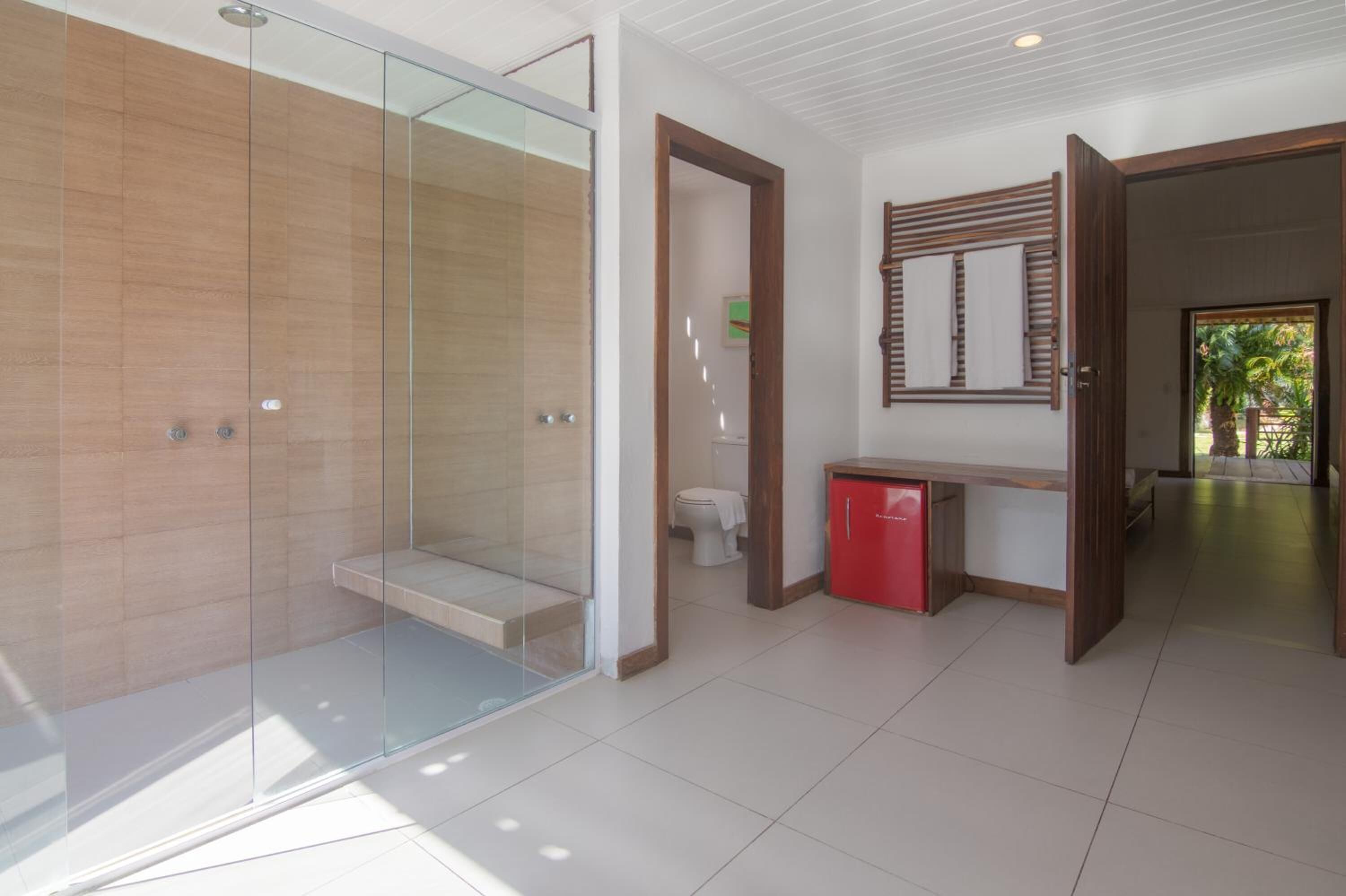 A modern bathroom with a glass shower enclosure, a toilet, and a small red cabinet.