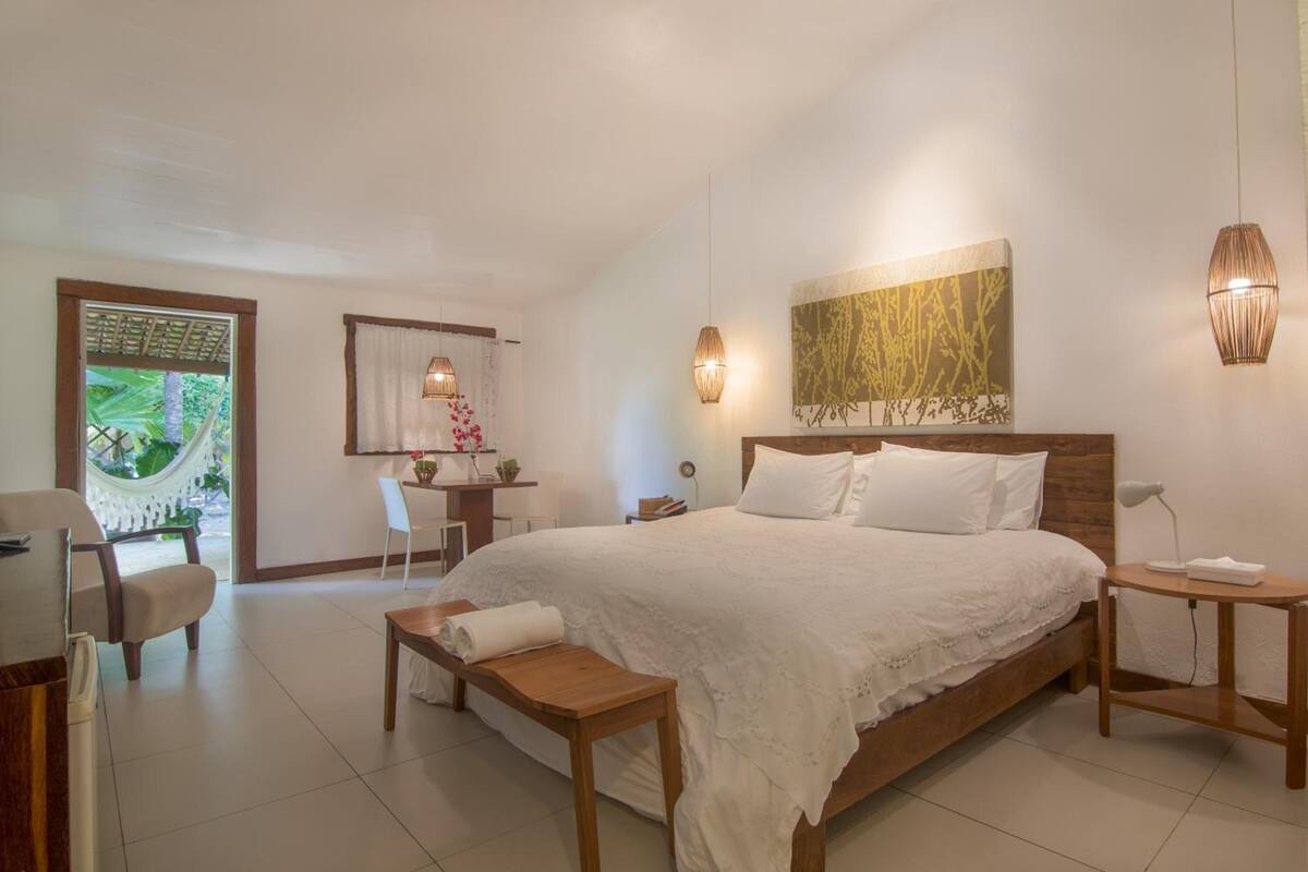 A bedroom with a large bed, bedside tables, a desk, and a chair.