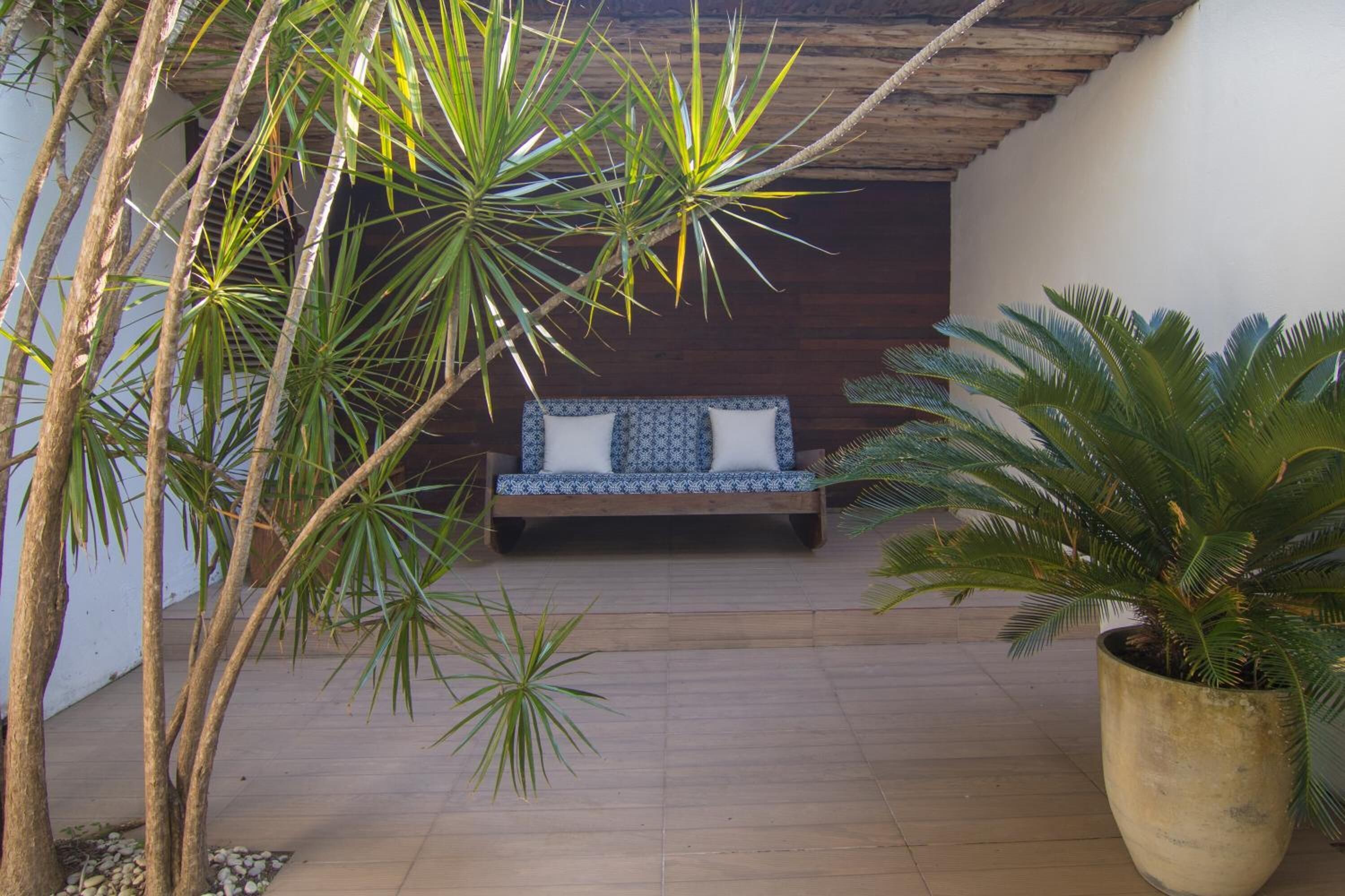 A wooden deck with a blue patterned sofa and a large potted plant.