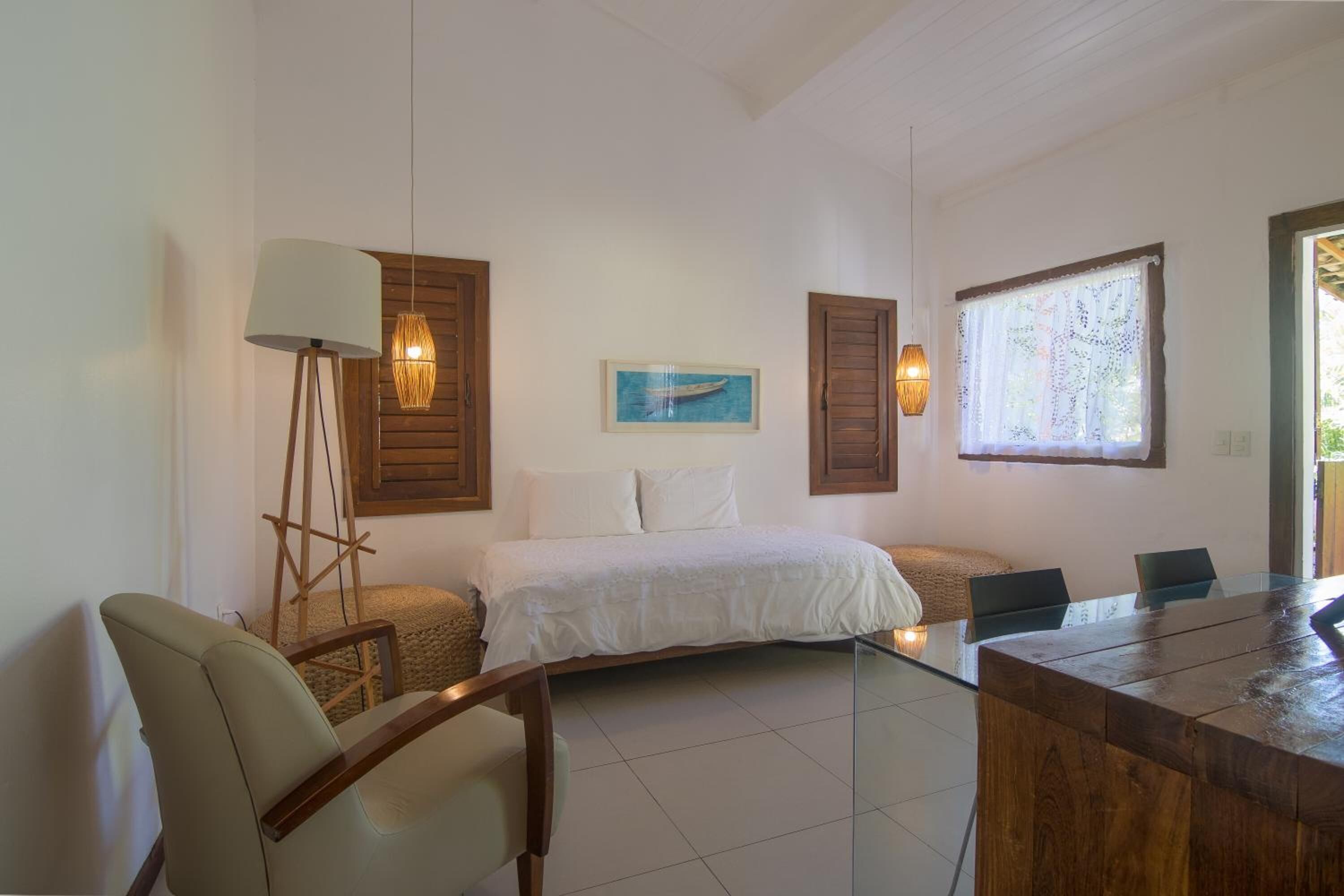 Ein Schlafzimmer mit Bett, Schreibtisch, Stühlen, einer Lampe und einem Gemälde an der Wand.