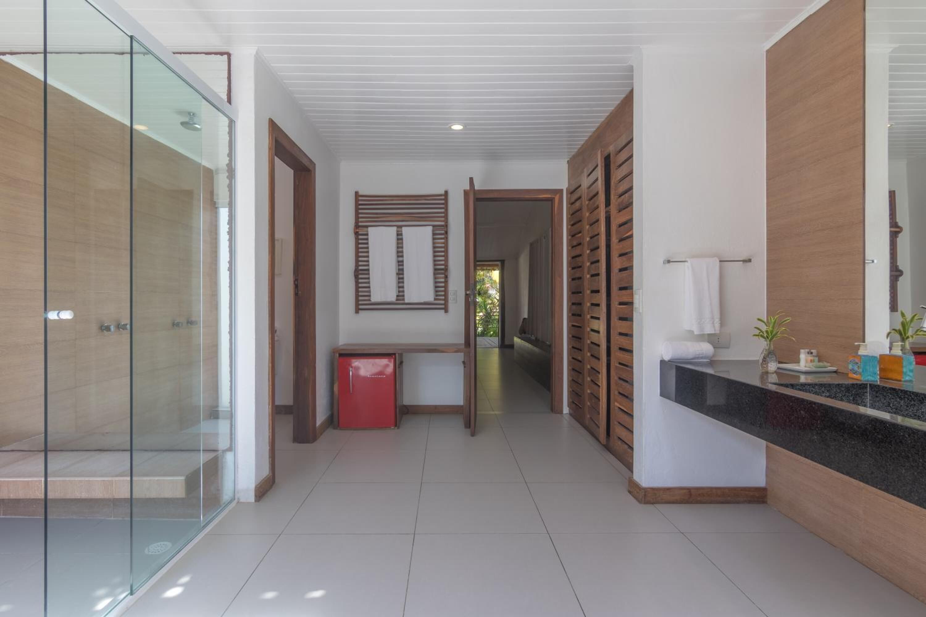 Un baño moderno con cabina de ducha de vidrio, tocador de madera con encimera negra y un espejo.