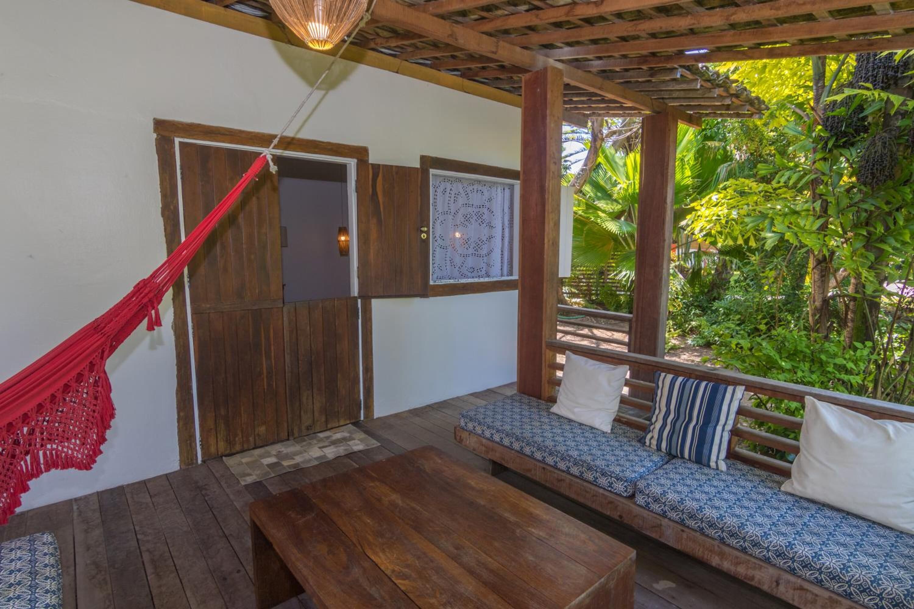 Une terrasse en bois avec un hamac, un banc et un coin salon confortable agrémenté de coussins à motifs.