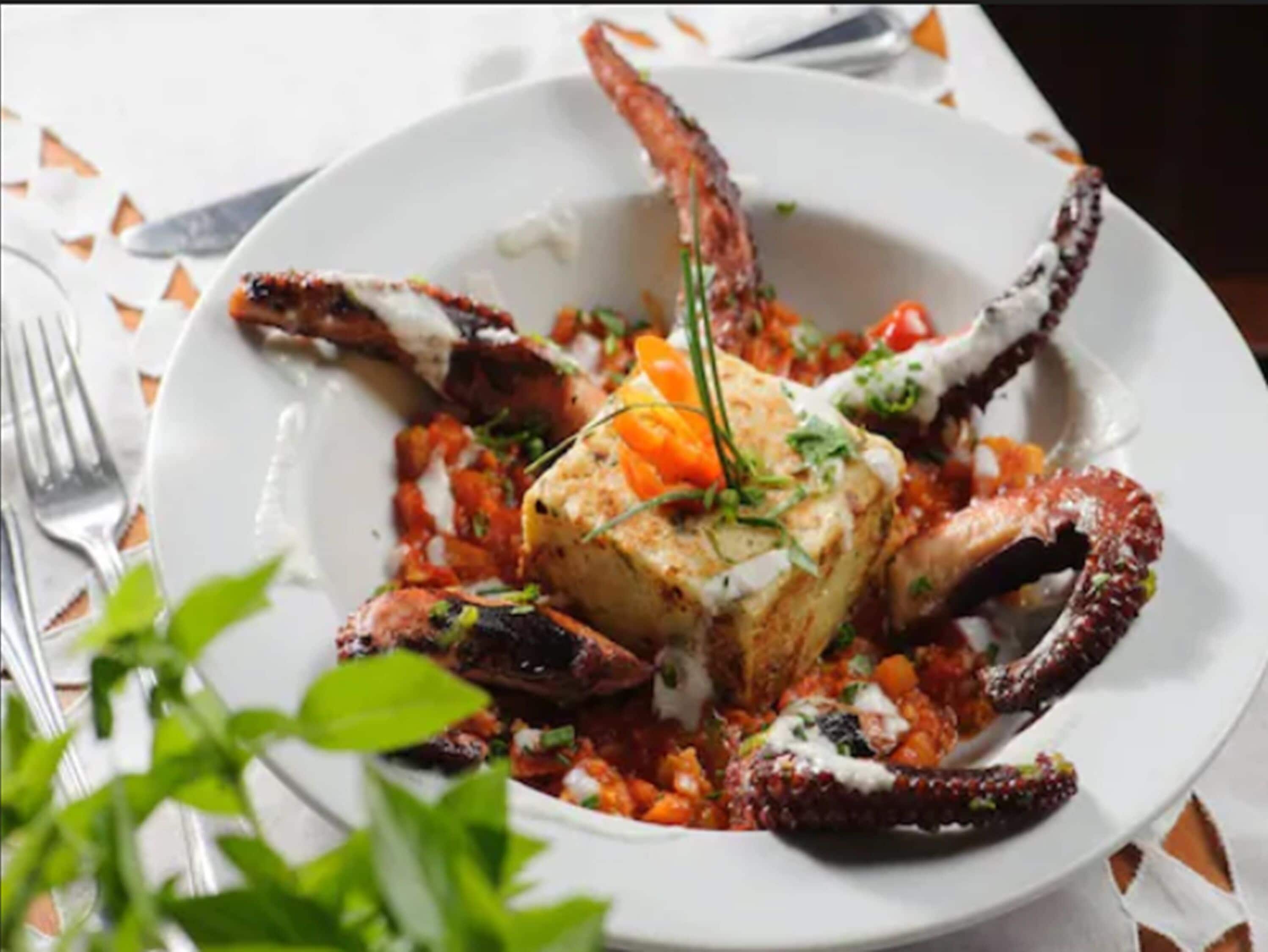 A plate of seafood with a large crab leg, a piece of fish, and a garnish of herbs.