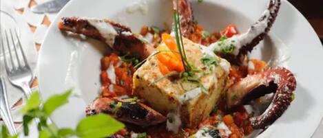 A plate of seafood with a large crab leg, a piece of fish, and a garnish of herbs.