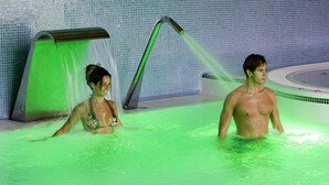 Una piscina con un ligero tono verdoso, una zona de duchas y paredes de azulejos.