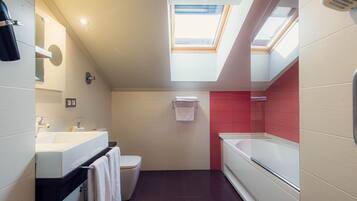 Un bagno moderno con una finestra a soffitto, una vasca, un water e un mobile lavabo con specchio.