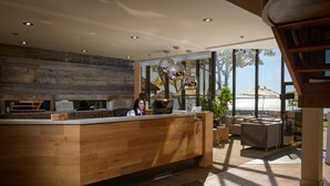 Un mostrador de recepción con detalles de madera, un ventanal con vistas al mar y un diseño de interiores moderno que incluye un sofá y una mesa de centro.