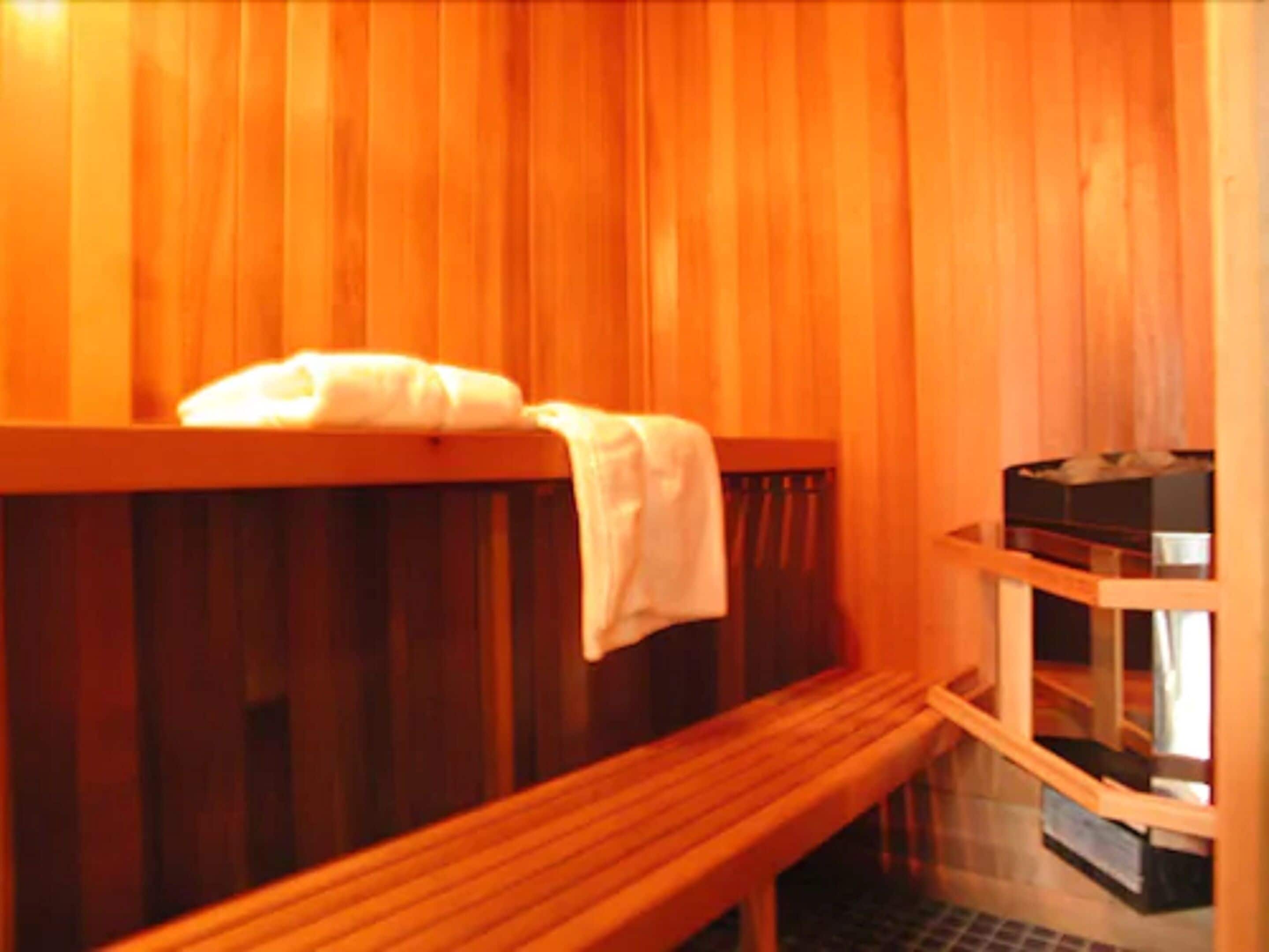 Een houten sauna met banken en een bankje met een handdoek.