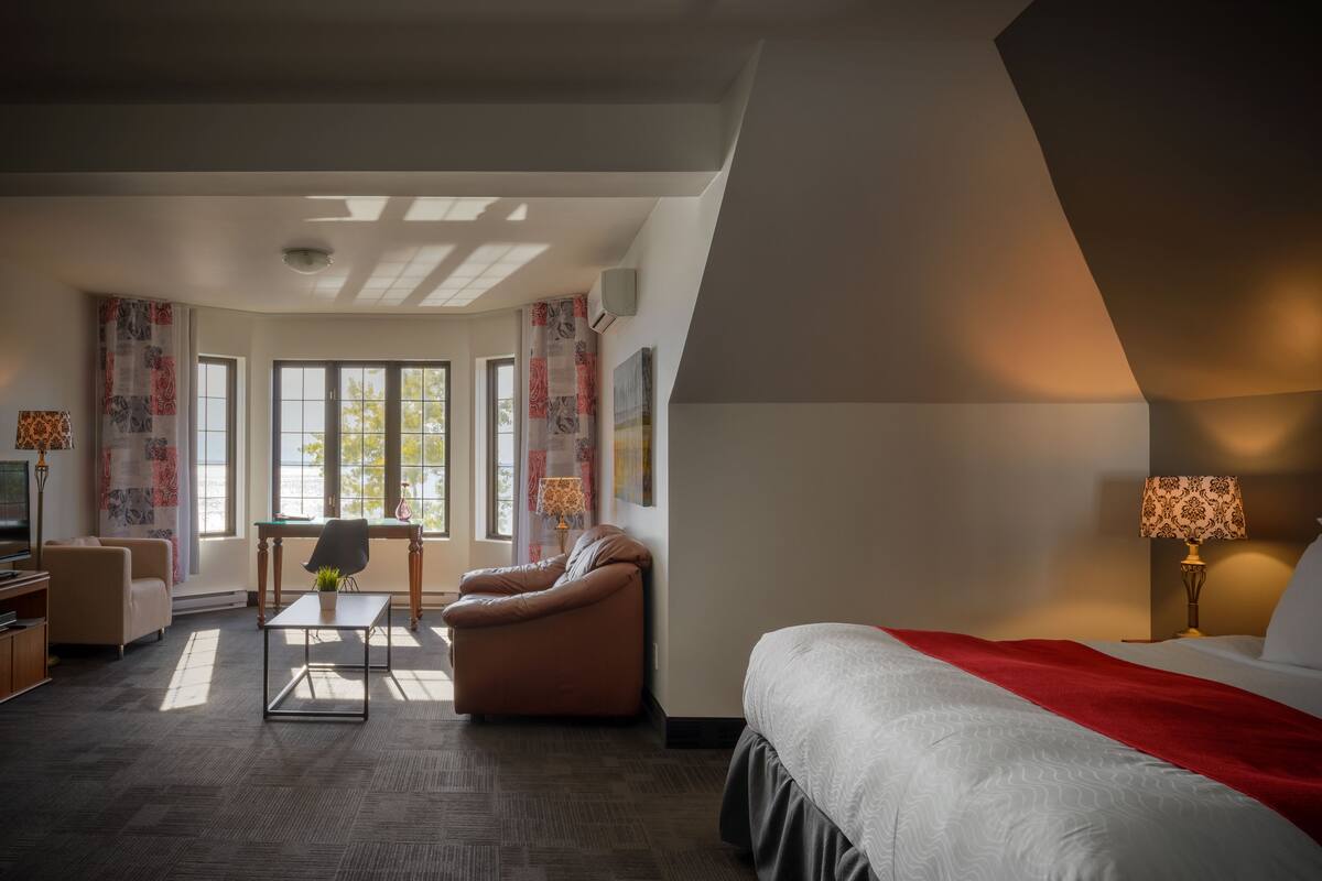Ein modernes Hotelzimmer mit einem großen Bett, einer Couch, einem kleinen Tisch und einem Fernseher.