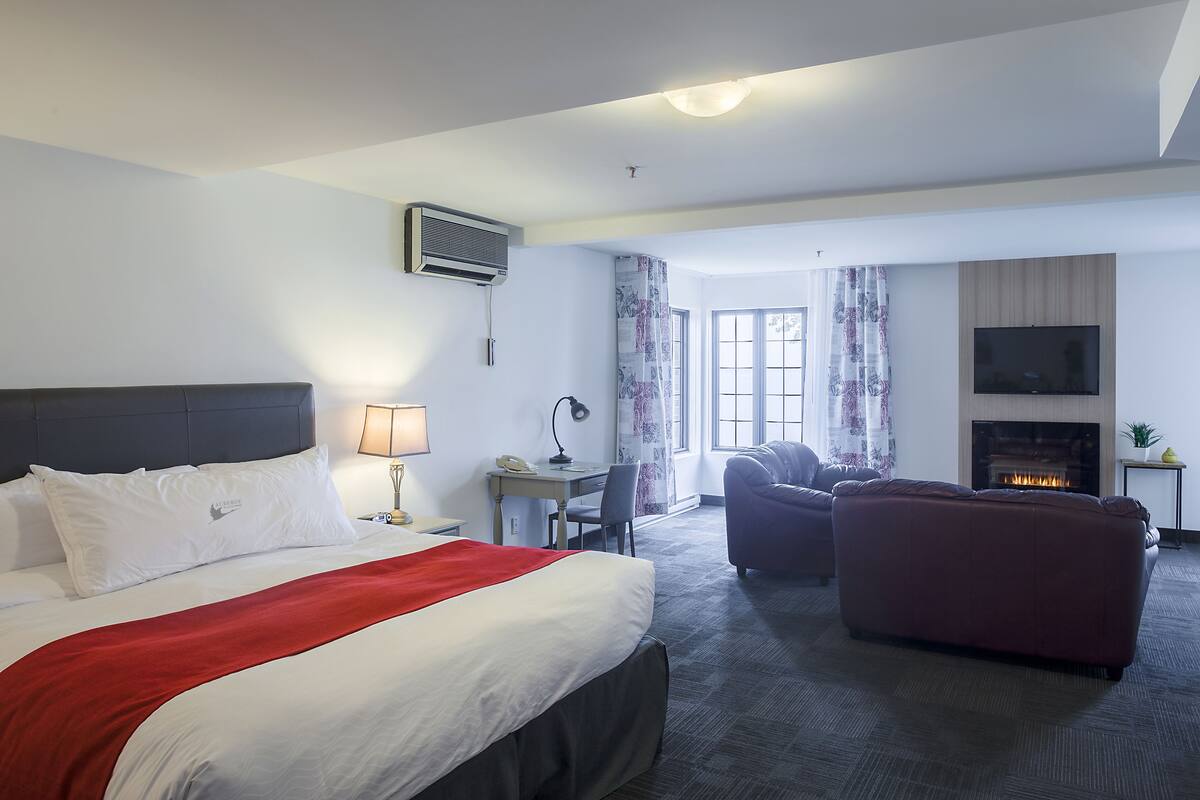 Ein Hotelzimmer mit Bett, Schreibtisch, einer Couch und einem Kamin.