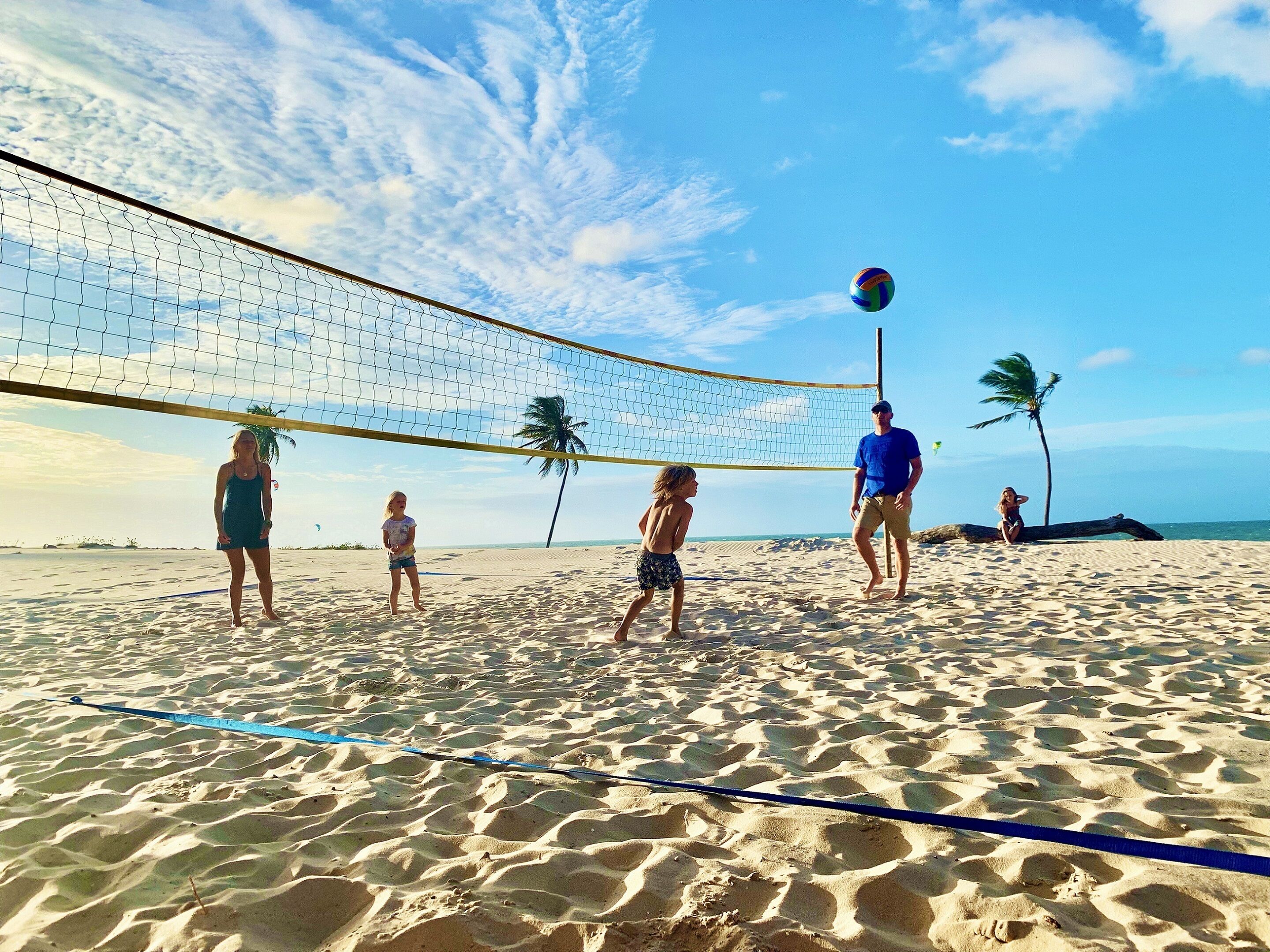 A beach volleyball game with players and a net on a sandy beach.