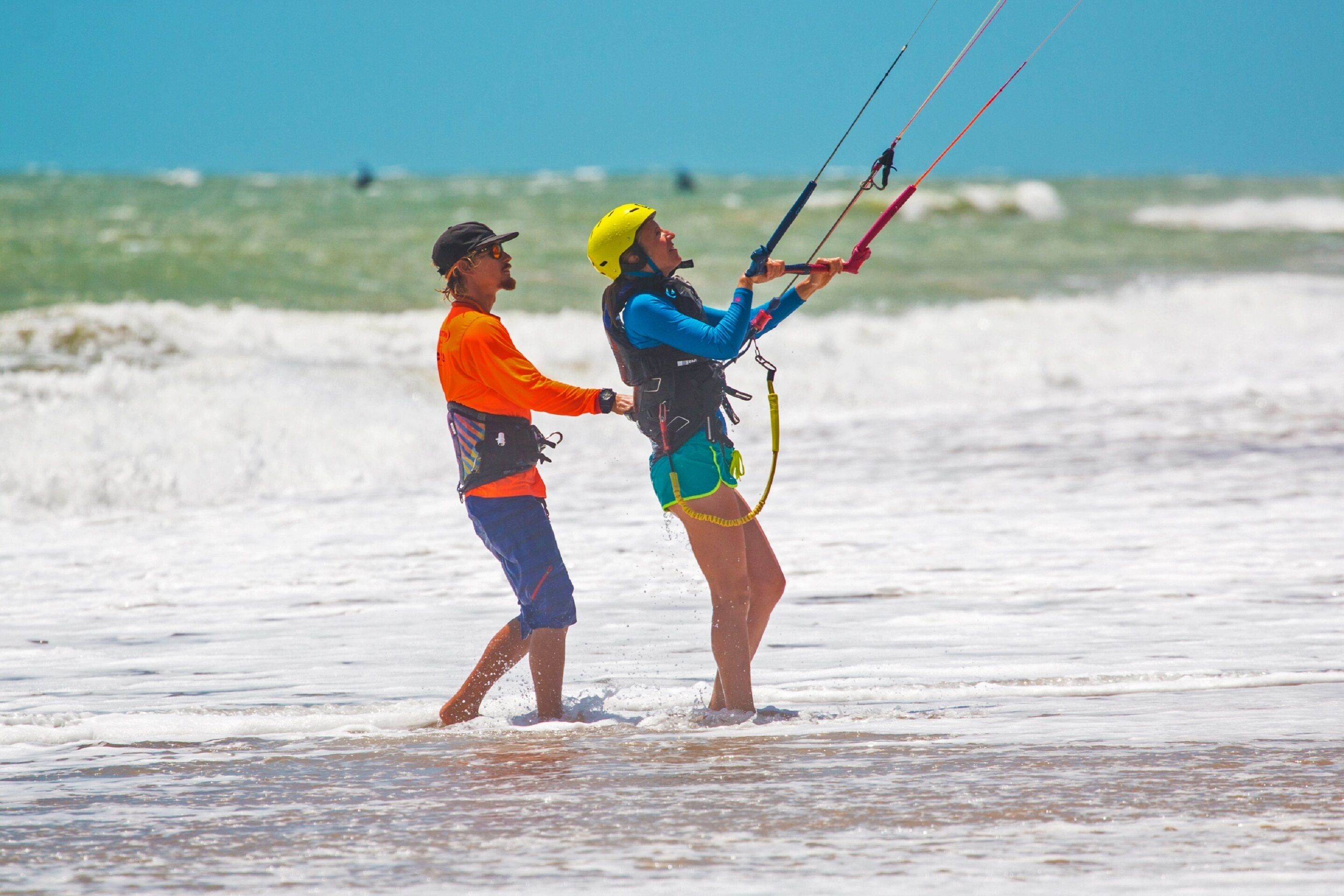 Two people walking on a beach with a kiteboard.
