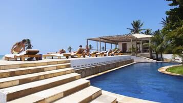 Una piscina al aire libre, sillones reclinables de piscina