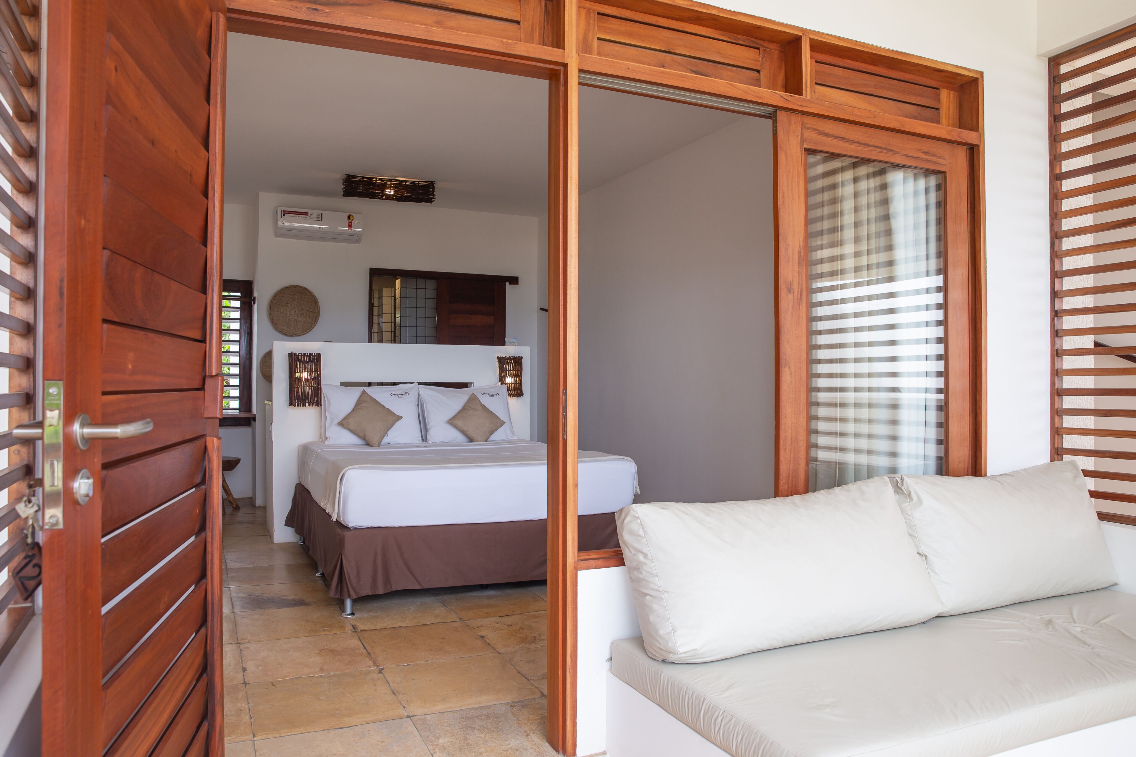 Een slaapkamer met een bed, een bank en een houten deur.
