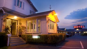 Un motel composé d’un bâtiment à deux étages, doté d’une entrée bien visible et d’une enseigne lumineuse indiquant son nom.