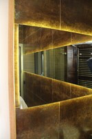 Un bagno con uno specchio grande, pareti piastrellate e un portasciugamani.