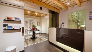 Een modern receptiegebied met een houten plafond, een receptiebalie en ingelijste foto’s aan de muur.