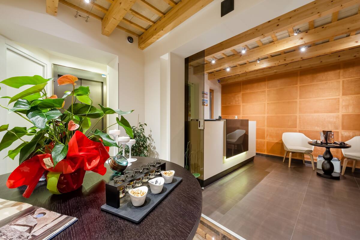 A modern interior with a round table set for dining, a potted plant with red flowers, and a wooden wall.