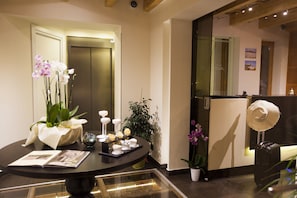 A reception area with a reception desk, a glass display case, a potted plant, and a door to the elevator.