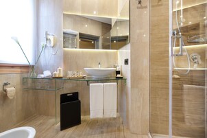 A modern bathroom with a glass sink, a large mirror, and a walk-in shower.