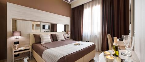 Una habitación de hotel moderna con una cama grande, una mesita de noche, una lámpara y una pequeña mesa con una botella y un vaso.