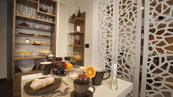 Una tavola imbandita per la colazione, con pasticcini, bevande e un pannello decorativo bianco.
