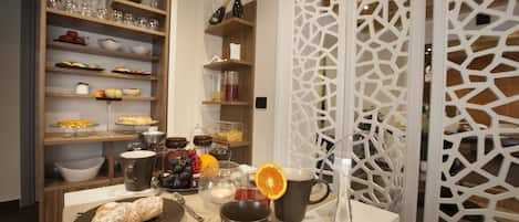 A breakfast table with pastries, drinks, and a decorative white partition.