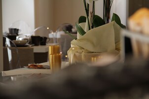 A table with a white orchid, a stack of gold-colored candles, and a glass container with cookies.