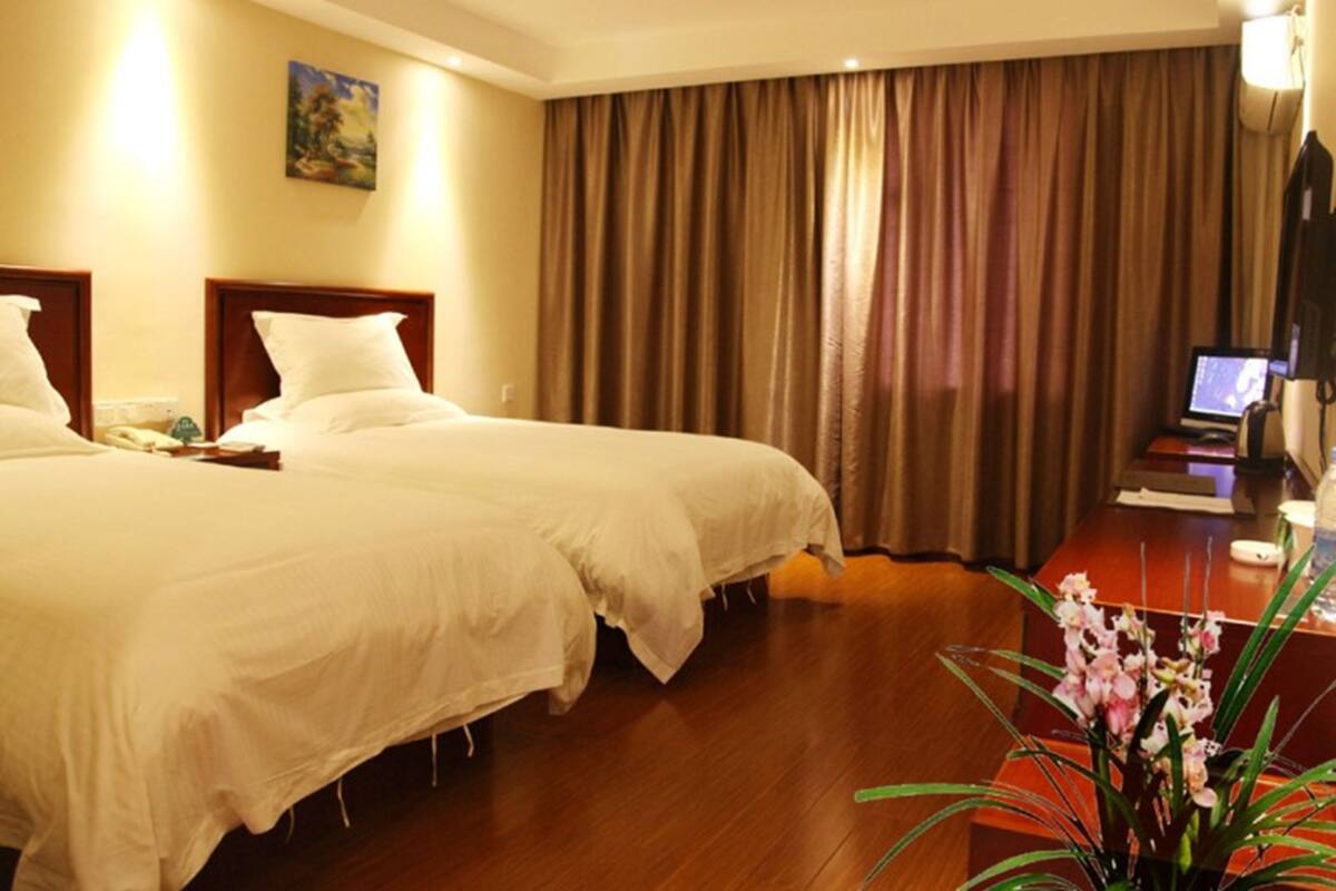 A hotel room with two beds, a desk with a computer, a lamp, and a painting on the wall.
