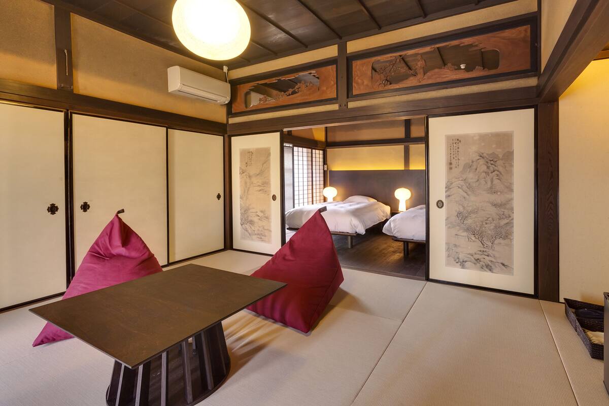 A traditional Japanese-style room with tatami flooring, a low table, and two red cushions.