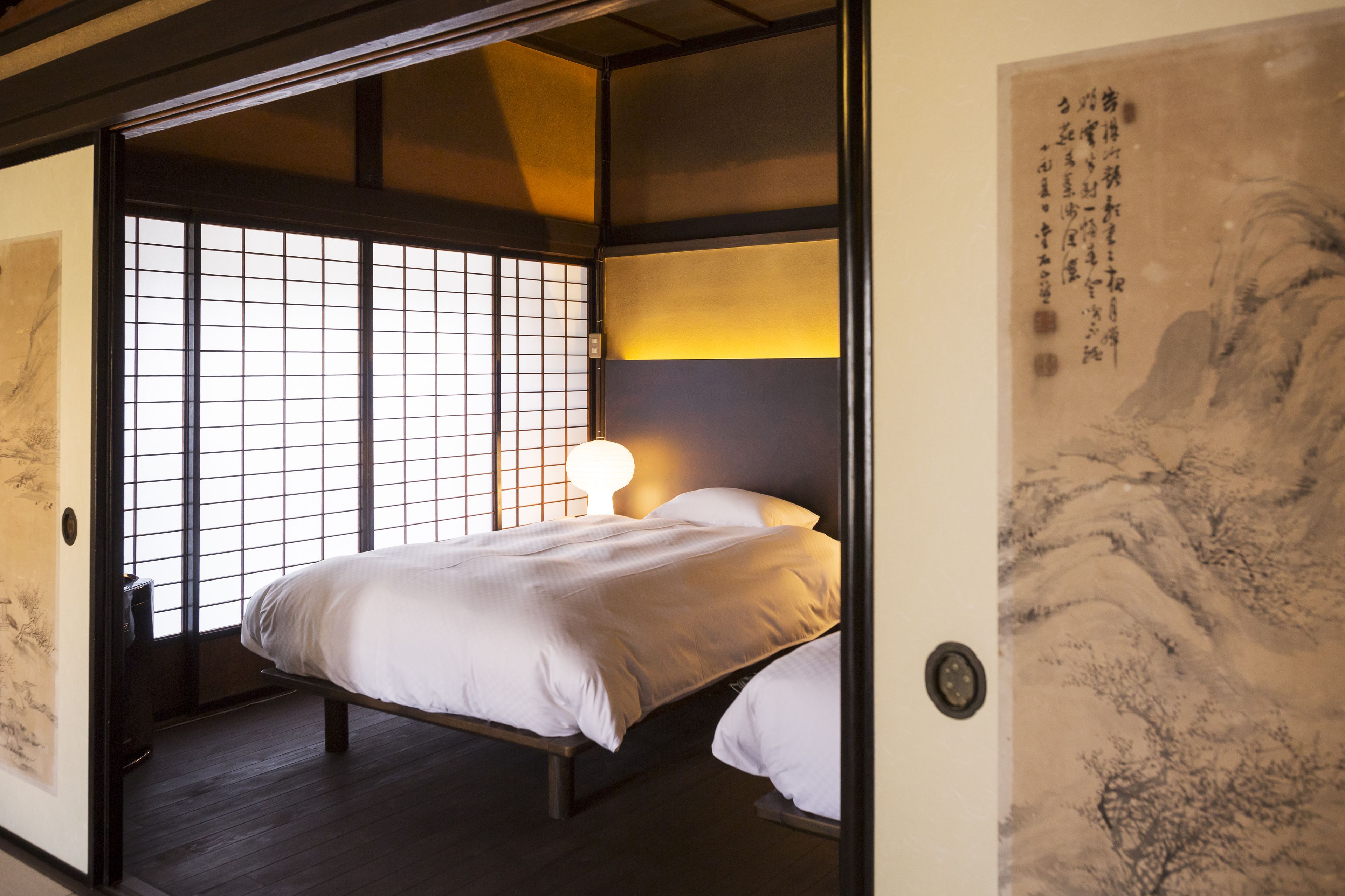 Un dormitorio de estilo japonés tradicional con suelo de tatami, una cama baja y puertas correderas.